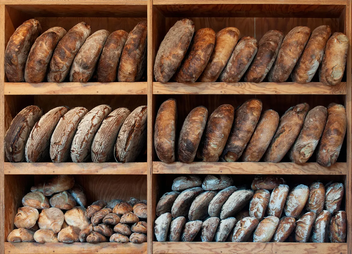 Wooden shelves stacked with rustic sourdough loaves