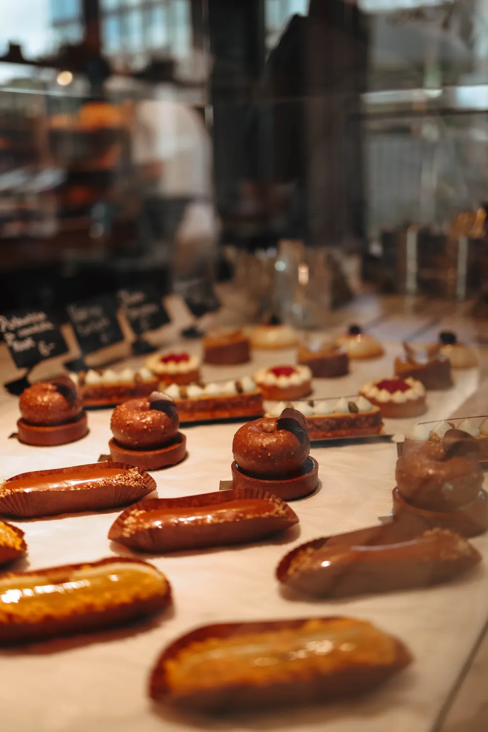Éclairs and cream puffs lined up on the pastry counter